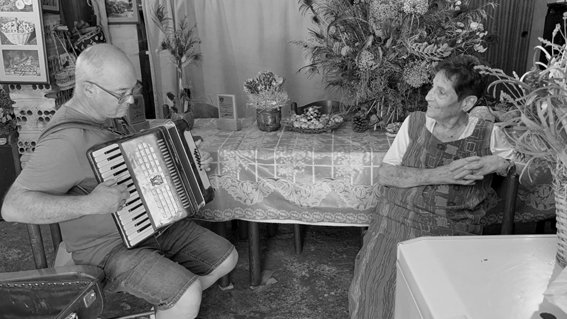 Josep Garcia fent sonar l'acordió d'en Fonso de Lliurona, amb la Maria Quintana (Arxiu del Grup dde Recerca Folklòrica de la Garrotxa - Santi Plana, 2025).